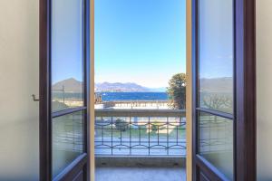 une porte ouverte s'ouvrant sur un balcon avec vue sur l'océan. dans l'établissement Palazzo BellaVista by Impero House, à Stresa