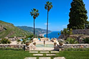 un jardin avec des palmiers et une piscine dans l'établissement The Ashbee Hotel, à Taormine
