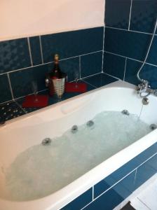 uma banheira com uma garrafa de vinho em 2 chambres doubles, 1chambre 4 lits simples, Salle de bains avec balnéo thérapie em Plaine-Haute