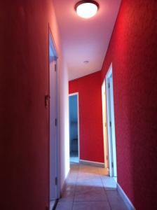 um corredor vazio com uma parede vermelha e uma porta em 2 chambres doubles, 1chambre 4 lits simples, Salle de bains avec balnéo thérapie em Plaine-Haute