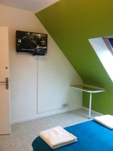 Grünes Zimmer mit einem Bett und einem TV an der Wand in der Unterkunft 2 chambres doubles, 1chambre 4 lits simples, Salle de bains avec balnéo thérapie in Plaine-Haute