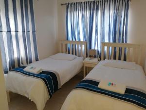 two beds in a room with blue curtains at 24B Kruger Cottage in Mossel Bay