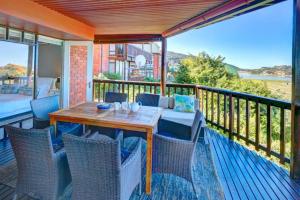 a patio with a wooden table and chairs on a balcony at Wilderness Views Self Catering Apartment in Wilderness