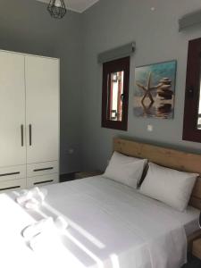 1 dormitorio con 1 cama blanca grande con almohadas blancas en Light blue house 3 Apartments, en Poulithra