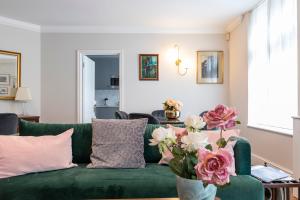 a living room with a green couch and flowers at Beautiful 2 bed apt in the heart of Mayfair, close to Tube in London