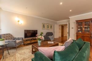 a living room with a green couch and a tv at Beautiful 2 bed apt in the heart of Mayfair, close to Tube in London