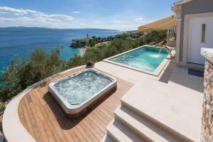a hot tub on a deck with a view of the water at Villa Sapore di Sale with Pool in Bol
