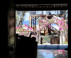una ventana con vistas a un jardín con flores rosas en Villa Sunset Beach en Gili Trawangan