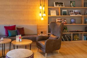 a living room with a couch and a chair and tables at HELDs Vitalhotel in Ruhpolding