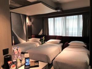 香港的住宿－憙酒店，酒店客房设有三张床和窗户。