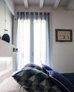 a bedroom with a window with blue curtains and a bed at Calida B&B in Castellammare del Golfo