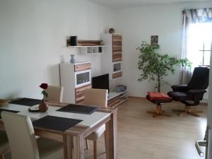ein Wohnzimmer mit einem Tisch und Stühlen sowie eine Küche in der Unterkunft Ferienwohnung Sonne-Stadtrand Dresden in Moritzburg