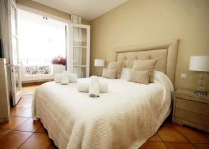- une chambre avec un grand lit blanc et une fenêtre dans l'établissement Jardines de las Golondrinas Marbella with Sea Views, à Marbella