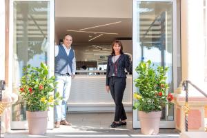 a man and a woman standing in front of a building at Albergo Pesce D'oro in Verbania