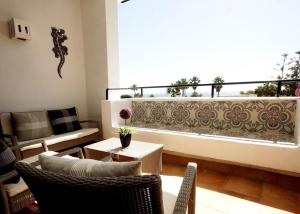 a living room with a balcony with a couch and a table at Jardines de las Golondrinas Marbella with Sea Views in Marbella