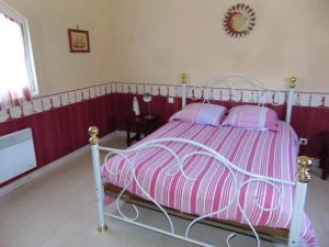 a bedroom with a pink and white bed with pink pillows at LA MARVINIERE in Saint-Bonnet-sur-Gironde