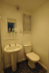 a white bathroom with a toilet and a sink at The Sandhill in Sandown