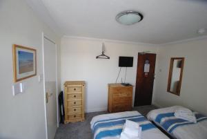 a bedroom with two twin beds and a dresser at The Sandhill in Sandown