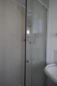 a shower with a glass door next to a sink at The Sandhill in Sandown