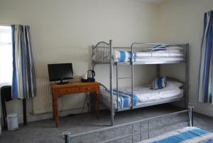 a bedroom with two bunk beds and a desk with a computer at The Sandhill in Sandown
