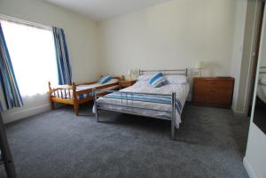 a bedroom with a bed and a chair and a window at The Sandhill in Sandown