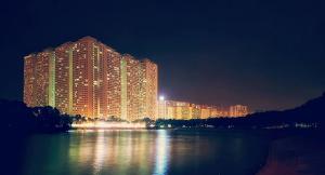 a large building with lights on the water at night at Ruby Lakeview homestay in Hanoi