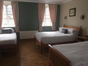 1 dormitorio con 2 camas y 2 ventanas en Riverside Guesthouse, en Charlestown