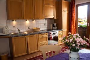 a kitchen with wooden cabinets and a table with a vase of flowers at Haus Wendelin in Fulpmes