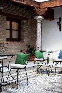 格拉納達的住宿－卡薩奎斯塔德爾瓜公寓酒店，庭院里摆放着带绿色枕头的椅子