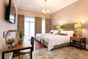 a bedroom with two beds and a table and a mirror at The Rasmus in Pretoria