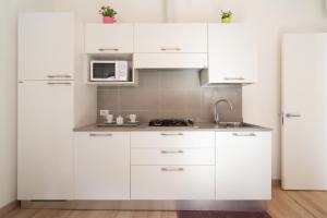 cocina con armarios blancos y nevera blanca en Serenissima Apartments, en Venecia