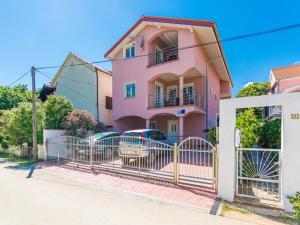 une maison rose avec une clôture devant elle dans l'établissement Apartments Trogrlic, à Privlaka