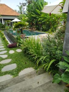 einen Garten mit Pool und einigen Pflanzen in der Unterkunft Uma Dhari Villa by Prasi in Ubud