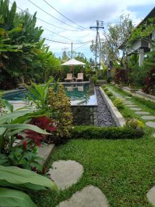 einen Garten mit einer Terrasse und einem Tisch mit einem Sonnenschirm in der Unterkunft Uma Dhari Villa by Prasi in Ubud