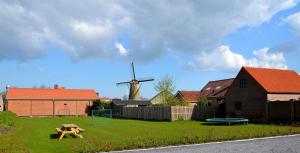 a playground with a windmill in a yard with a house at De Meulestee in Ouddorp