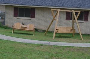 two benches sitting in the grass in front of a house at Ouachita Mountain Inn in Glenwood