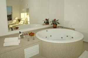 a white bath tub sitting next to a white sink at Vitória Hotel Convention Indaiatuba in Indaiatuba