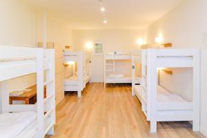 a room with several white bunk beds in it at SLO Living Hostel in Lyon