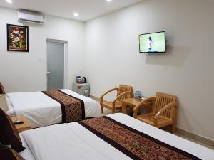 a hotel room with two beds and a tv on the wall at Minh Manh Hotel in Pleiku