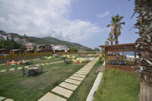 a resort yard with tables and chairs and palm trees at Marbella Kale Beach in Akçakale