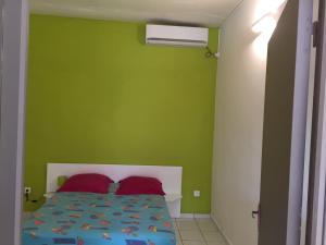 Un dormitorio con una pared verde y una cama con almohadas rojas. en COSY Tamarins 2 plage à quelques mètres à pied, en Sainte-Anne
