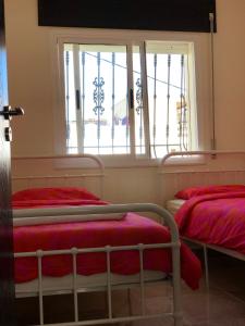 two beds in a room with a window at First Floor Apartment Family Layout in Oued Laou