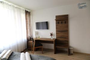 a bedroom with a desk and a tv on a wall at Gästehaus Zeppelin in Uhingen