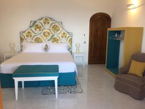 a bedroom with a large bed and a chair at Casa Antioco Original in Positano