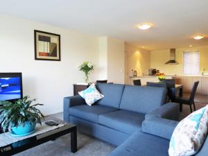 a living room with a blue couch and a table at Nesuto Newhaven in Auckland