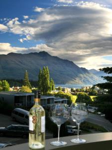 a bottle of wine and two wine glasses on a table at Cranbury Court Apartments in Queenstown