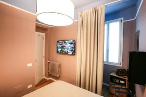 a living room with a television and a bed at Hotel Il Sole in Empoli