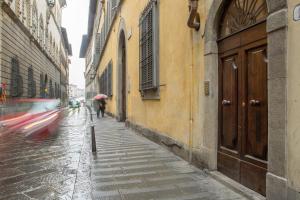 uma pessoa andando por uma rua com um guarda-chuva em Serragli Apartment em Florença