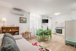a living room with a green table and a kitchen at Adeona apartments in Rijeka