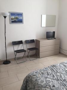 a bedroom with two chairs and a dresser with a television at Acquamarina in Levanto